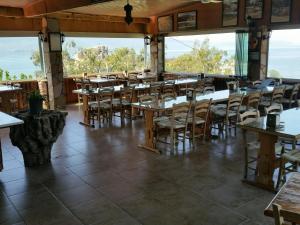 a restaurant with tables and chairs and large windows at Selenes Pansiyon in Kapıkırı