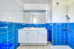 bagno piastrellato blu con lavandino e doccia di Studio avec piscine - proche plage a Soulac-sur-Mer