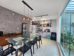 圣阿马鲁Eco House Gaivota - Cond Ville Portal das Dunas的厨房以及带玻璃桌和椅子的用餐室