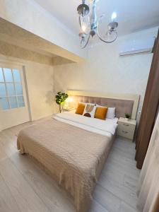 a bedroom with a large bed and a chandelier at Urban Oasis 216 in Almaty