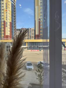 a car parked in a parking lot with tall buildings at Байсанат 1 in Zhezdi