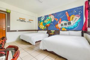 two beds in a room with a painting on the wall at Forever Happiness Hostel in Puli
