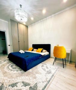 a bedroom with a blue bed and a yellow chair at Уютная квартира на Левом берегу, ТРЦ Хан Шатыр in Astana
