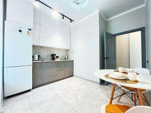 a kitchen with a table and a white refrigerator at Уютная квартира на Левом берегу, ТРЦ Хан Шатыр in Astana