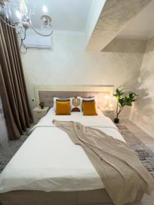 a bedroom with a large white bed with yellow pillows at Your Home Away from Home 213 in Almaty +8 photos