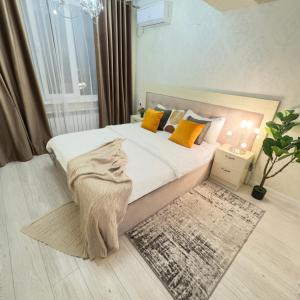 a bedroom with a bed with orange pillows and a rug at Your Home Away from Home 213 in Almaty