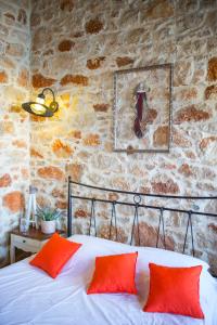 1 cama con almohadas rojas en una habitación con pared de piedra. en Halkis Muses, en Halki