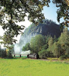 ein Zug, der die Gleise in der Nähe eines Berges entlangfährt in der Unterkunft Hotel BB in Olbersdorf