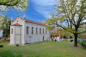 an old stone church with a tree in the yard at Apartman KALINA in Bileća