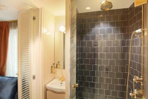 a bathroom with a black tiled wall and a shower at Makom Ferdinand Duval in Paris +43 photos