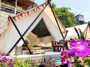 a tent in a garden with purple flowers at Dalana Coffee Camping Đà Lạt in Da Lat