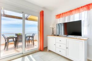 a living room with a tv and a sliding glass door at Villa Buraux III in Roses