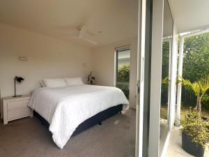 a bedroom with a bed and a large window at Easy Beach Holiday in Mount Maunganui