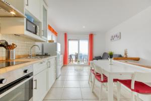 a kitchen with white cabinets and a table with red chairs at Villa Buraux III in Roses