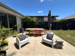 a patio with a table and chairs and an umbrella at Easy Beach Holiday in Mount Maunganui