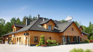 a log cabin with a sign on top of it at Karczma Dolina Pstrąga in Machowa