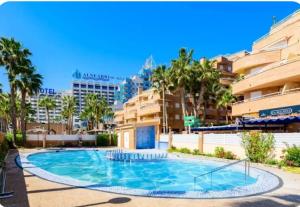 a pool in the courtyard of a building with palm trees at Apartamento Maru's in Oropesa del Mar