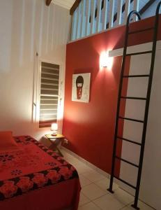a bedroom with a red wall with a bunk bed at Studio charmant avec piscine à Vieux-Habitants, 26 m² in Vieux-Habitants +5 photos
