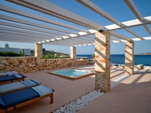 a patio with a pool and a stone wall at In Paros, fantastic waterfront villa in Parikia