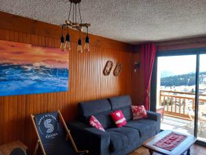 a living room with a blue couch and a balcony at Appartement chalet en plein centre des Saisies in Hauteluce