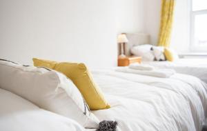 two white beds with yellow and white pillows at Old Vicarage Mortehoe Near Woolacombe 2 x sleeps 4 and 1 x sleeps 10 cottages in Mortehoe