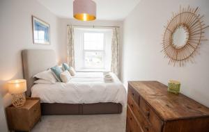 a bedroom with a bed with a window and a mirror at Old Vicarage Mortehoe Near Woolacombe 2 x sleeps 4 and 1 x sleeps 10 cottages in Mortehoe