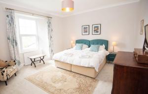 a bedroom with a large bed with a blue headboard at Old Vicarage Mortehoe Near Woolacombe 2 x sleeps 4 and 1 x sleeps 10 cottages in Mortehoe
