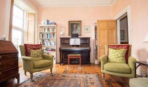a living room with a piano and two chairs at Old Vicarage Mortehoe Near Woolacombe 2 x sleeps 4 and 1 x sleeps 10 cottages in Mortehoe