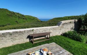 a picnic table with a bench next to a wall at Old Vicarage Mortehoe Near Woolacombe 2 x sleeps 4 and 1 x sleeps 10 cottages in Mortehoe