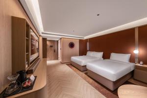 上海Crystal Orange Hotel Shanghai International Tourism Resort Pudong Airport的有两张床和一台电视的酒店房间
