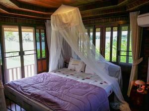 a bedroom with a bed with a mosquito net at Chuenwaree Riverside Stay in Suratthani