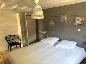 a bedroom with a large white bed and a chair at Superbe logement 5 places Chalet 5 in Banassac