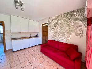 a living room with a red couch in a kitchen at Strawberry House in Colico