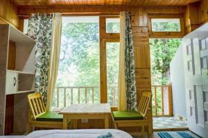 a bedroom with a table and chairs and a window at Ailyak Stays and Cafe, Shoja, Jibhi in Shoja