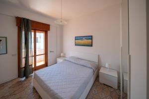a white bedroom with a bed and a window at Mati in Poesia - San Foca in Melendugno
