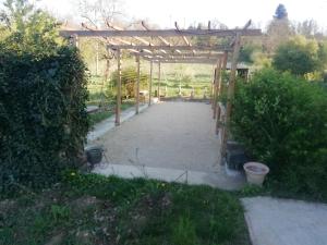 a garden with a wooden pergola and some bushes at Belle villa in Bourg-de-Péage