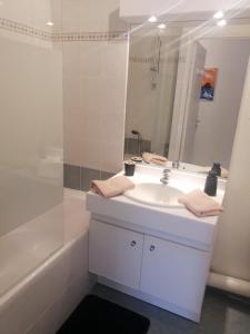 a white bathroom with a sink and a mirror at Appartement mandelieu in Mandelieu-la-Napoule