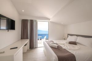 a white bedroom with a large bed and a large window at Vila Era Beach in Sarandë