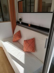 two orange pillows sitting on a white bench in a room at Lilalune in La Grande-Motte