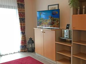 un salon avec une télévision à écran plat sur une armoire dans l'établissement Ferienhaus Nr 28, Kategorie Königscard, Feriendorf Hochbergle, Allgäu, à Lechbruck am See