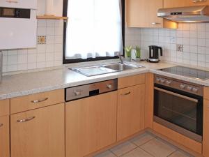 une cuisine avec des armoires en bois et un évier dans l'établissement Ferienhaus Nr 28, Kategorie Königscard, Feriendorf Hochbergle, Allgäu, à Lechbruck am See
