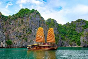 a boat with a large orange sail in the water at Roza Luxury Cat Ba - Cave hotel, Swimming Pool & Rooftop in Cat Ba