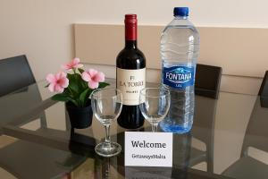 a bottle of wine and two glasses on a table at Blue Harbour 2 bedroom Seafront Apartments with large terrace with spectacular sea views - by Getawaysmalta in St. Paul's Bay +15 photos