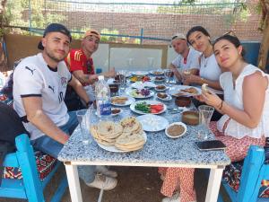a group of people sitting around a table with food at Mama Africa Camp in Luxor