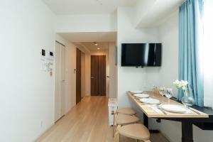 a room with a table with chairs and a tv on the wall at KINSHICHO Tokyo Holiday Hotel in Tokyo