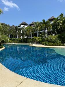 una piscina blu con palme sullo sfondo di Secret Garden at Bangtao Beach a Surin Beach