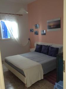 a bedroom with a bed with blue pillows and a window at Meltemia Studio Samos near the beach in Kámpos
