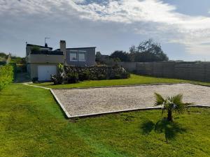 une cour avec une maison et un palmier dans l'établissement La palmeraie de brévy, à Réville
