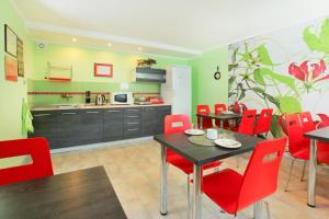 a dining room with red chairs and a kitchen at Willa JANECZKA in Karpacz