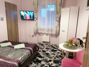 a bedroom with a bed and a tv on the wall at Willa JANECZKA in Karpacz